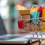 Mini koszyk sklepowy z produktami w środku przy komputerze